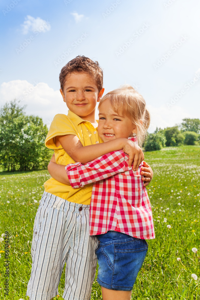 Boy and girl hugging in green field