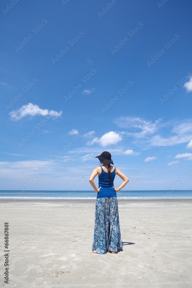 穿着夏装的年轻女子站在海滩上