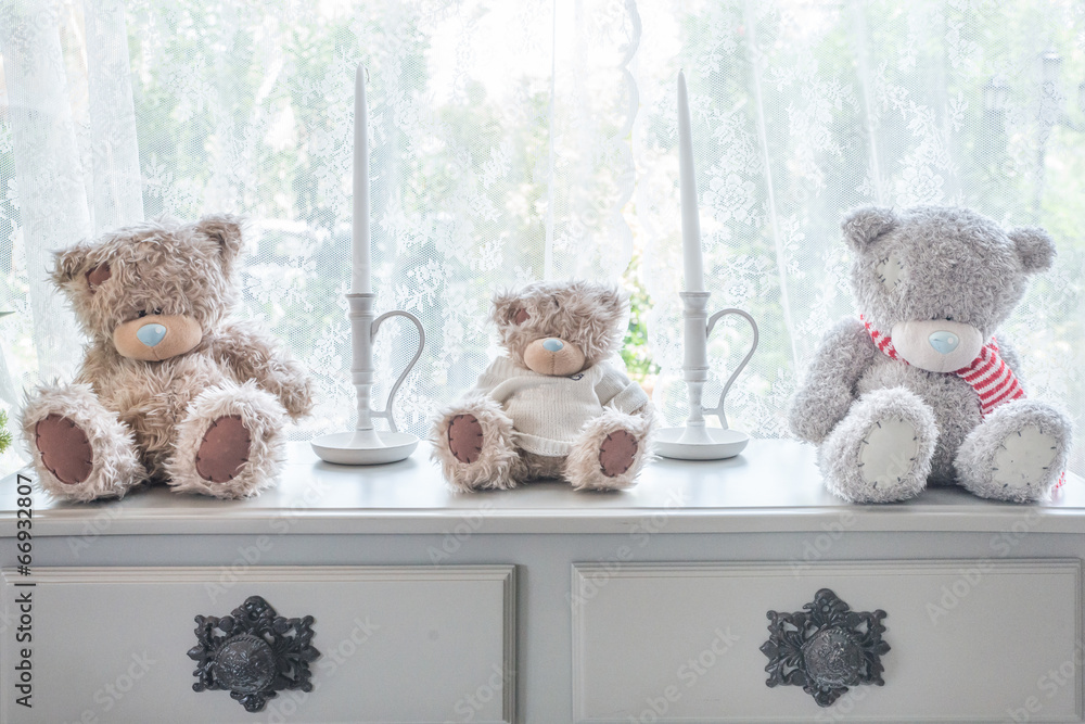 Many bear doll and candle on table and windowsill background