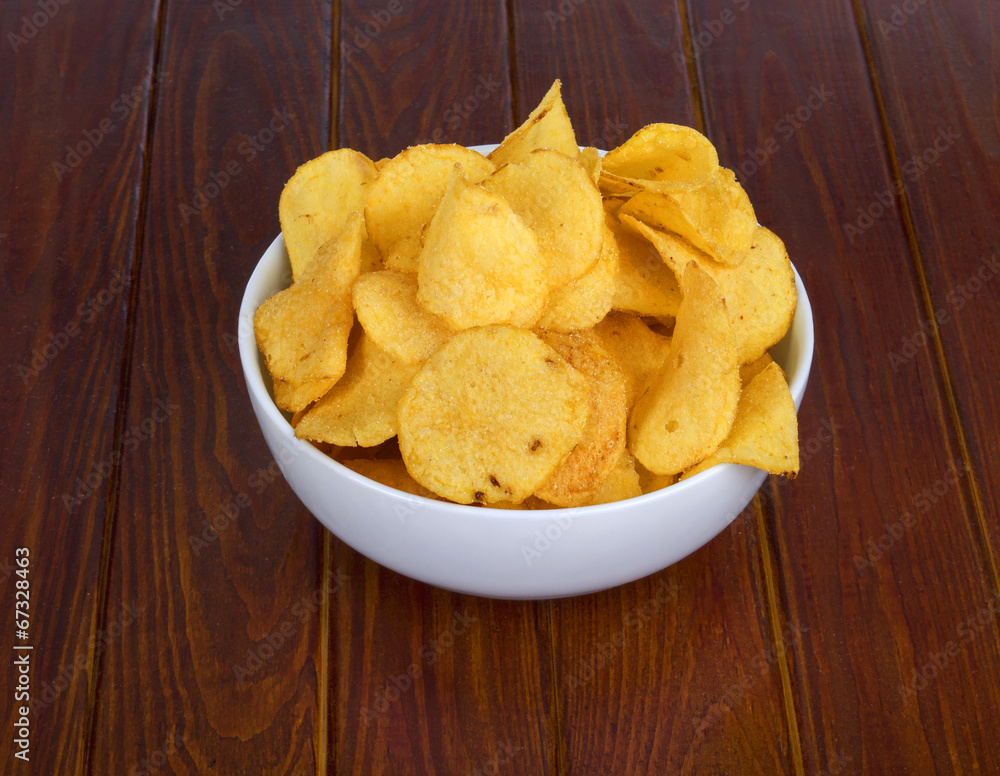 Flavored potato crisps in wooden bowl on table