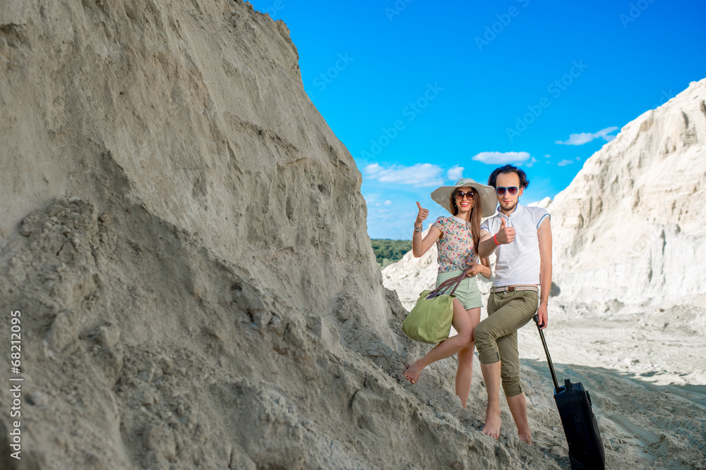 Young couple traveling on sandy locality with their baggage