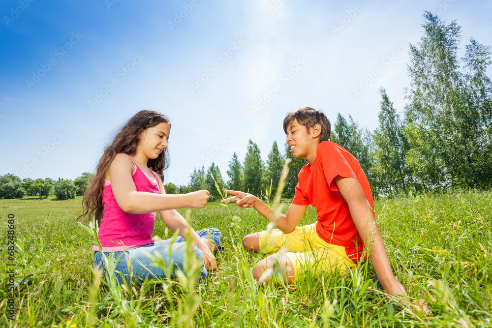 Children play rock-paper-scissors on grass