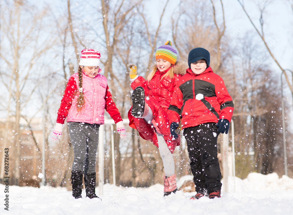 Boy and girls playing with snow in winter park