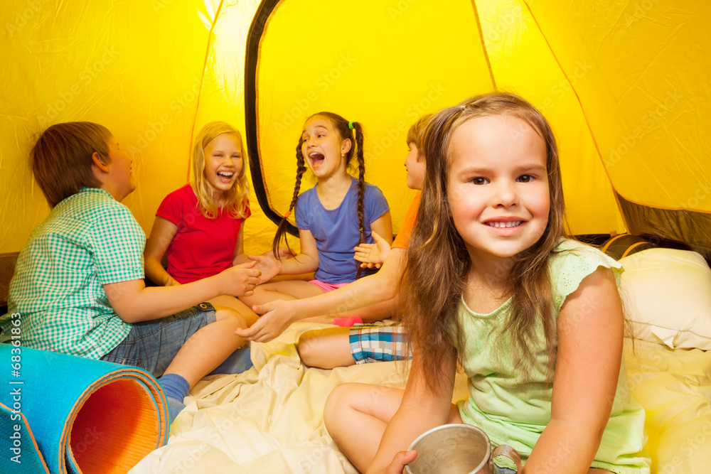 Five kids sit inside a yellow tent