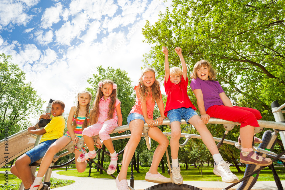 Kids sit on round bar of playground construction