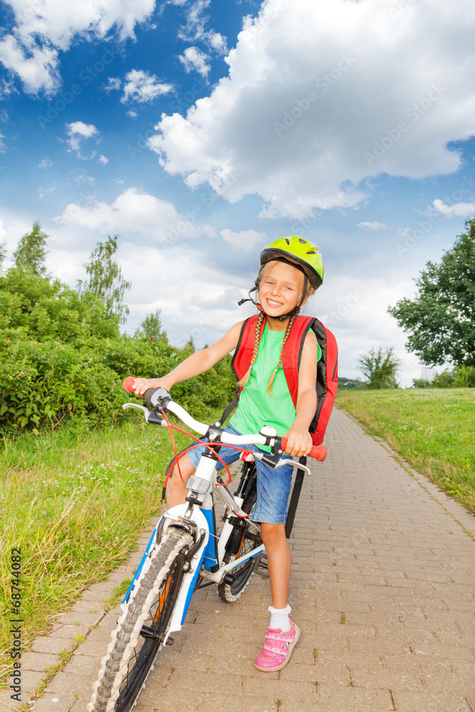 Happy blond girl with braids in bicycle helmet