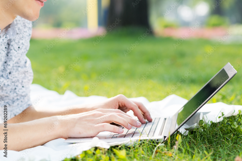 young man working in the park with a laptop