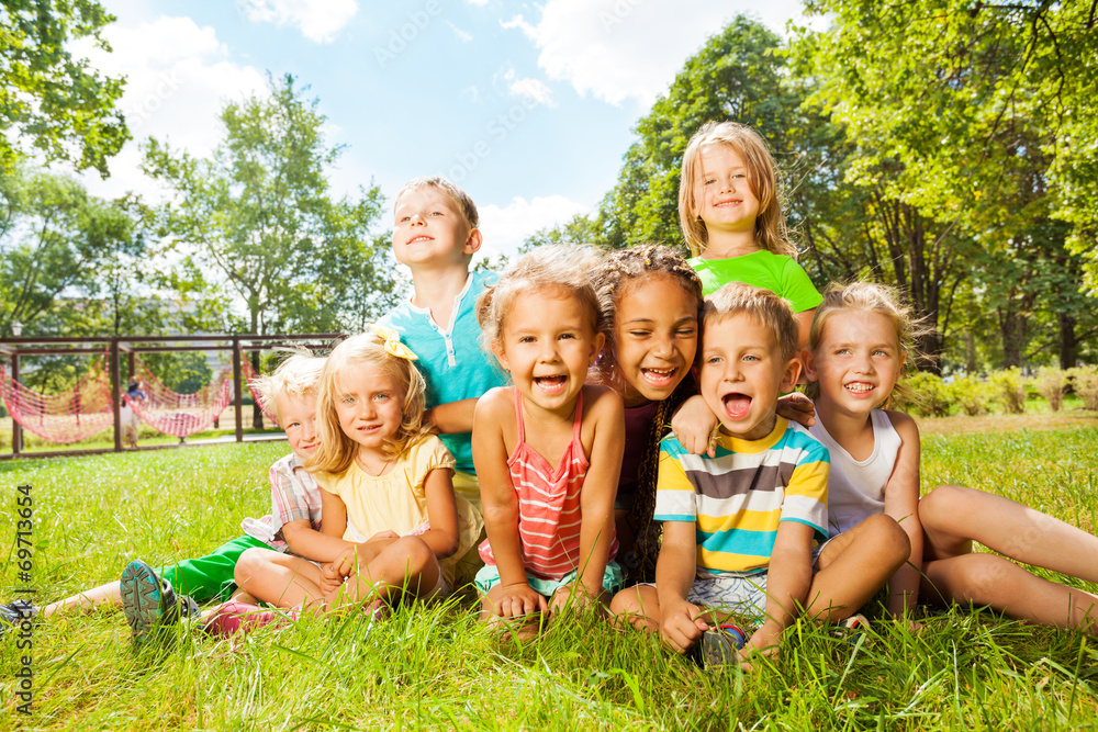 Group of happy little kids on the lawn in park