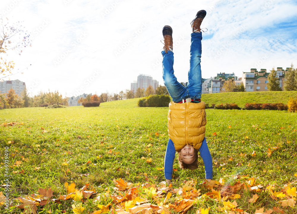 Boy stand on hands on the lawn