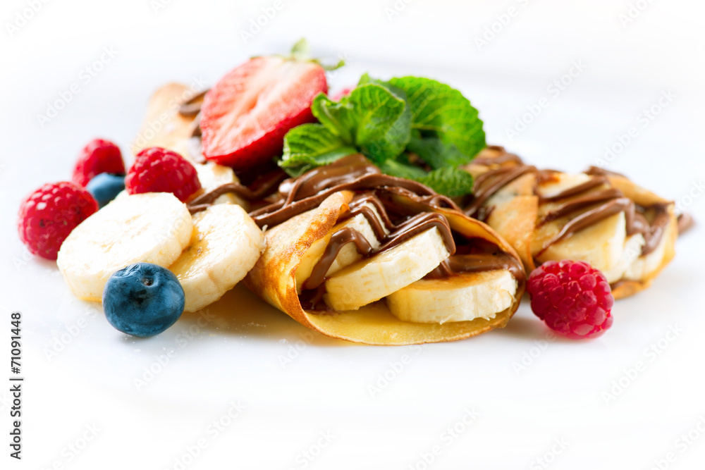 Crepes with banana, chocolate and berries closeup