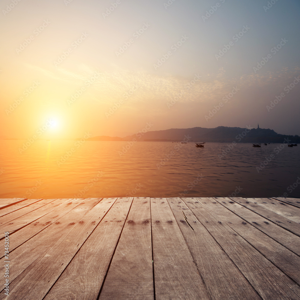 plank board with lake in sunset as background