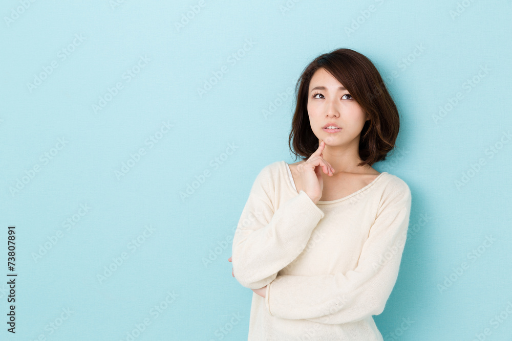 attractive asian woman thinking on blue background