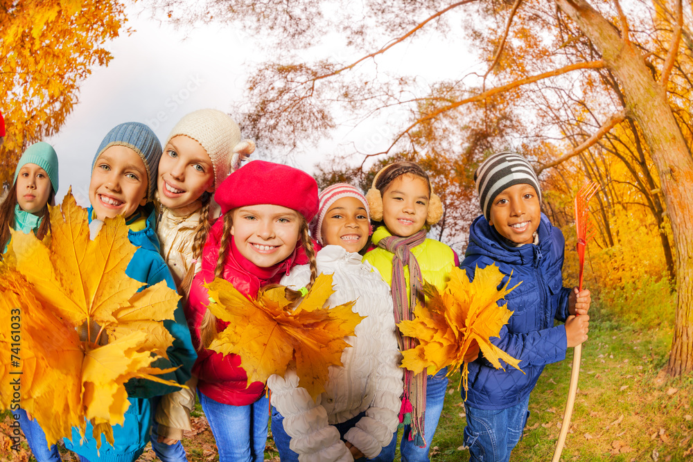 Smiling small children in park with yellow leaves