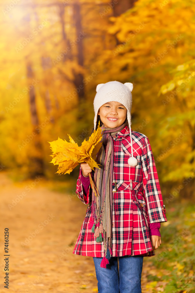 Cheerful Asian girl with bunch of yellow leaves