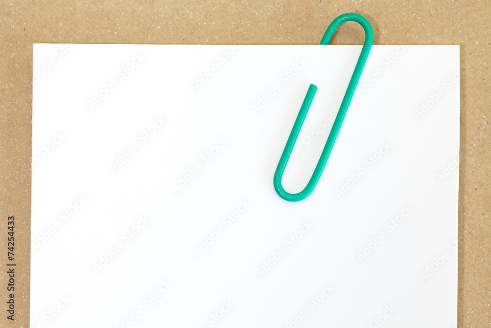 Green metal paper clip and blank white paper note