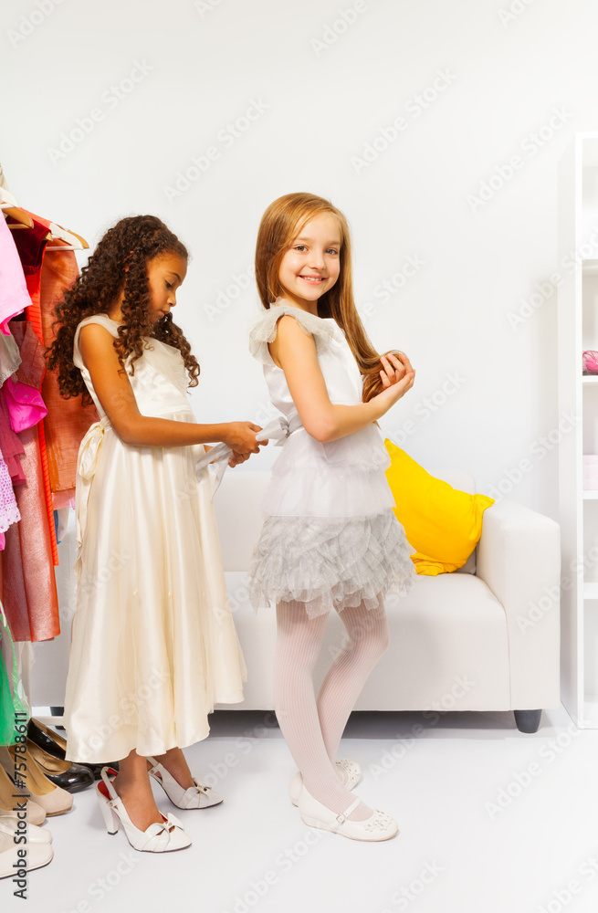 Small girl helps her friend by fitting the dress