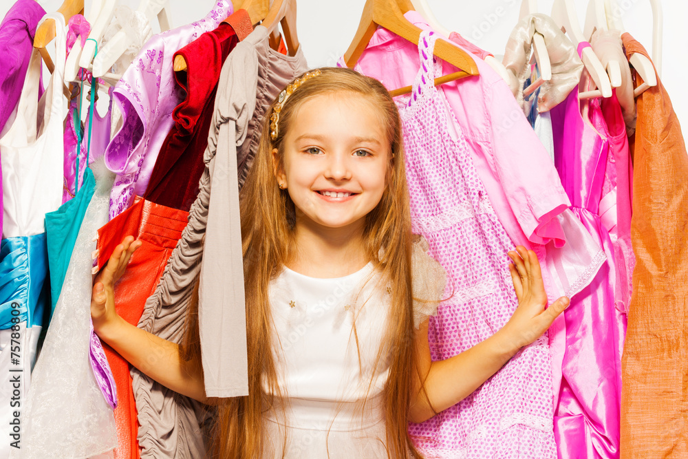 Cute girl standing between hangers during shopping