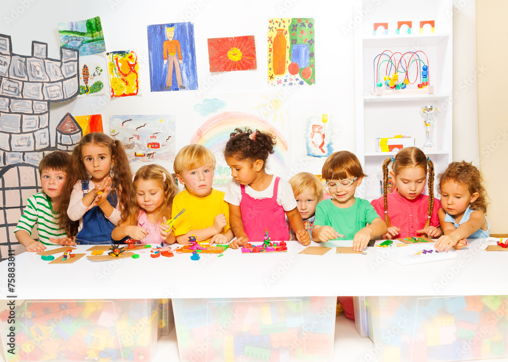 Large group of kids play with plasticine in class