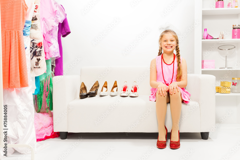 Girl with braids sits on sofa choosing high heels