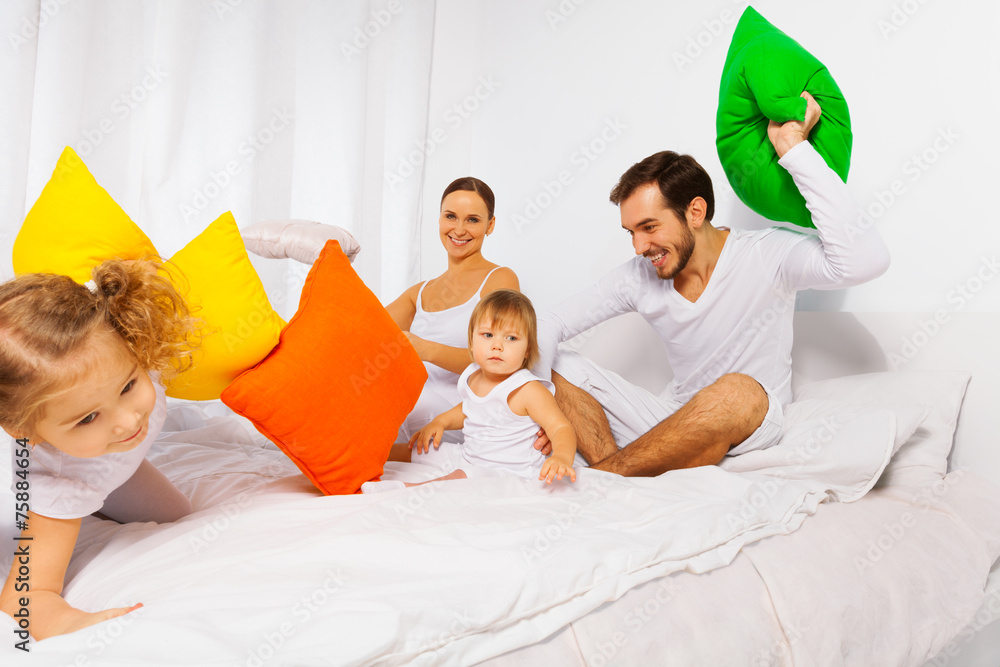 Happy father, mother and kids play with pillows