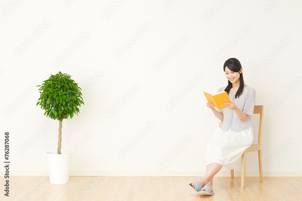 部屋で本を読む女性