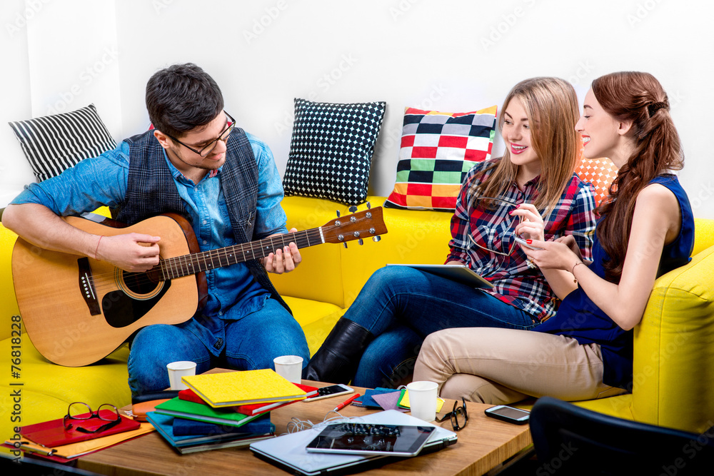 Man playing a guitar with girlfriends