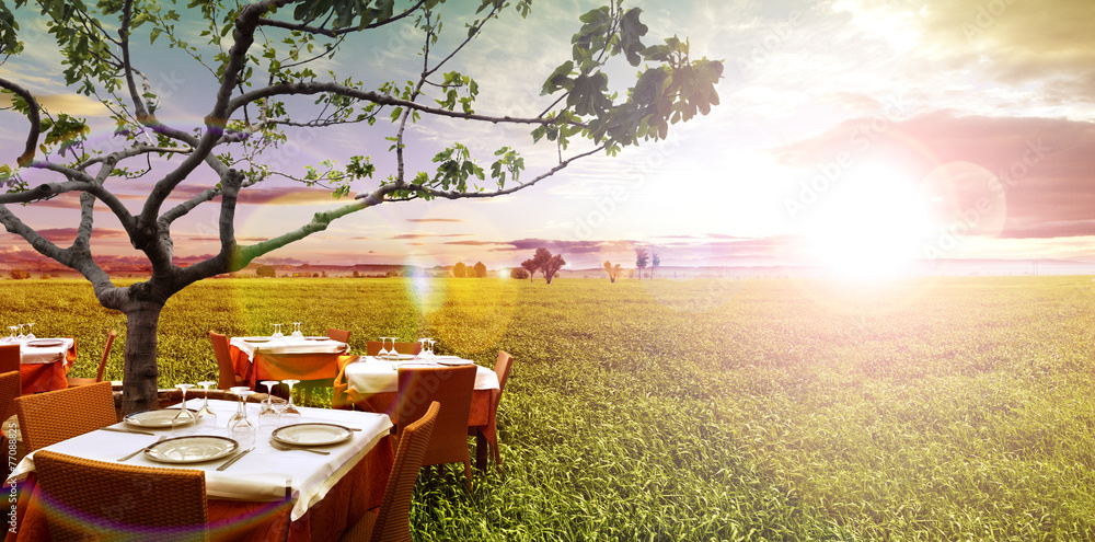 Restaurante al aire libre idílico y campos verdes.Puesta de sol