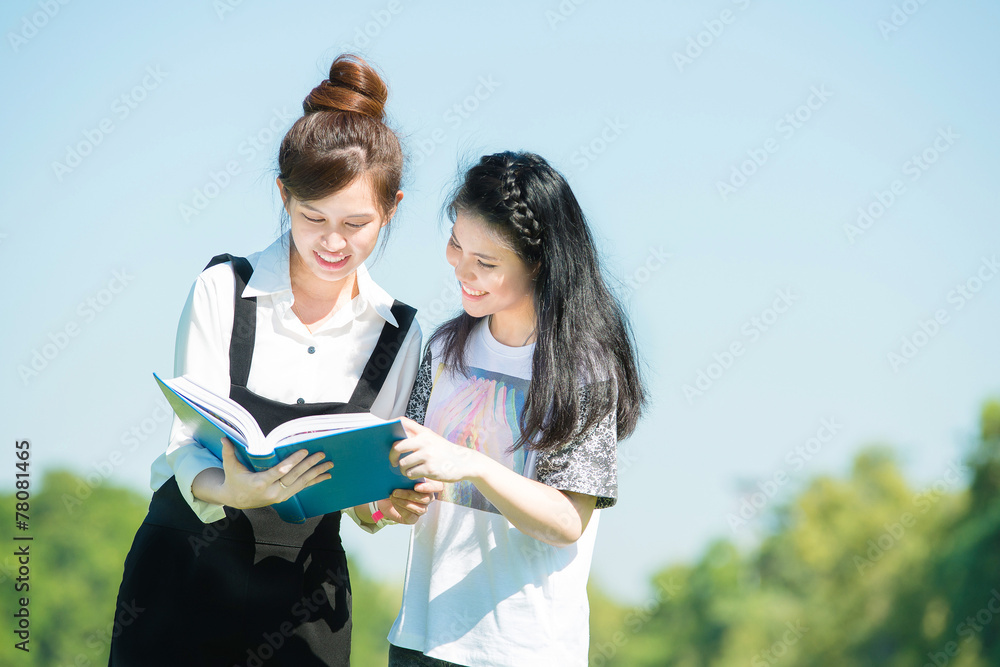 两名亚洲学生在公园看书