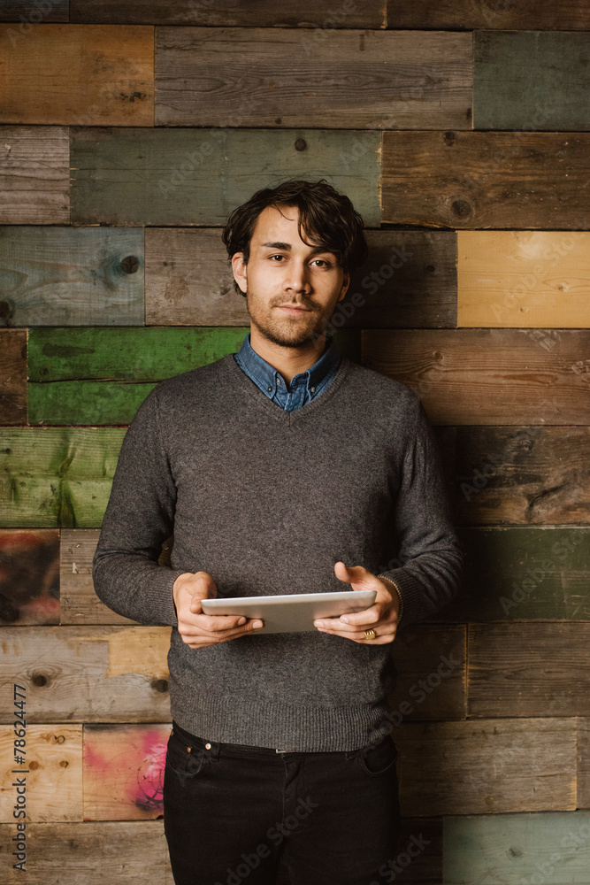 Confident young man holding a digital tablet in office