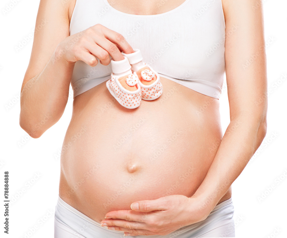 Pregnant woman holding baby shoes in her hands