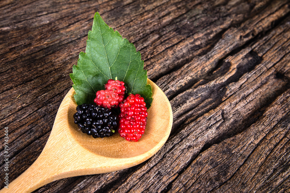 mulberry fruit in the wooden spoon on wood plate