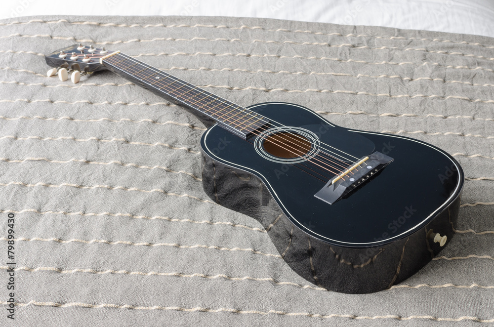 black acoustic guitar on bed