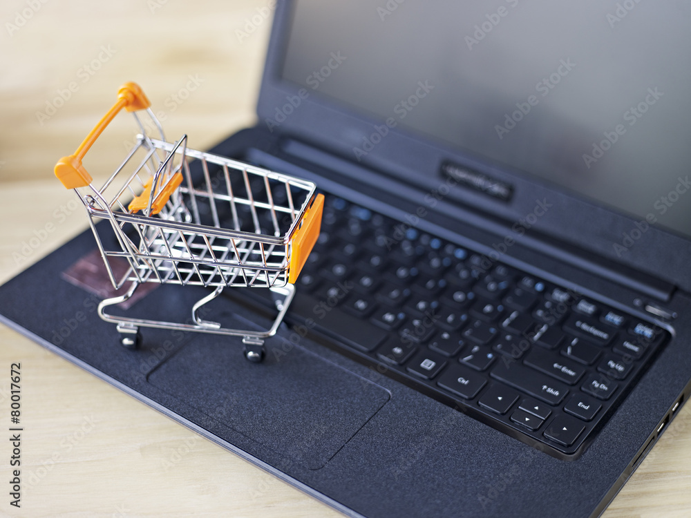 toy shopping cart on top of keyboard of laptop computer