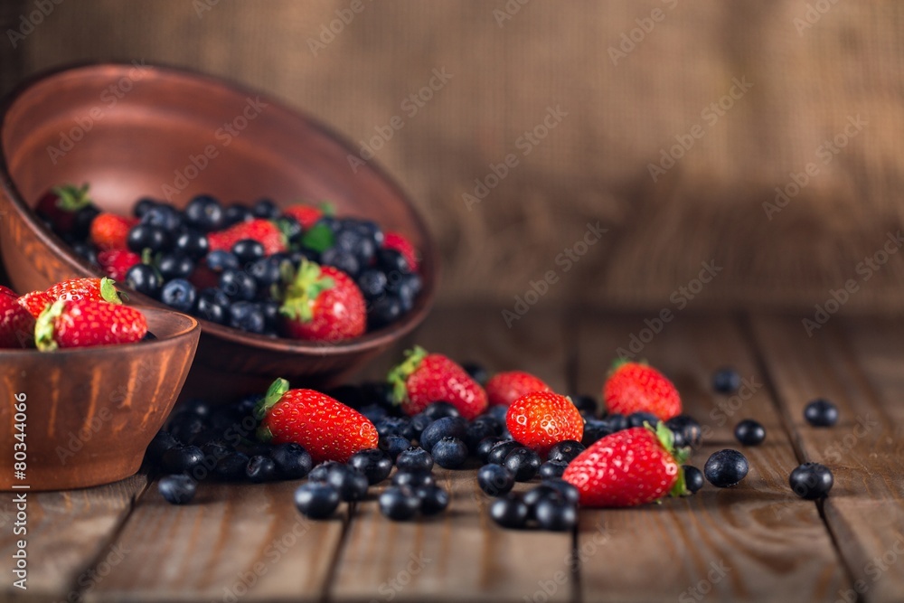 Assorted. Mix of fresh berries in a basket on rustic wooden