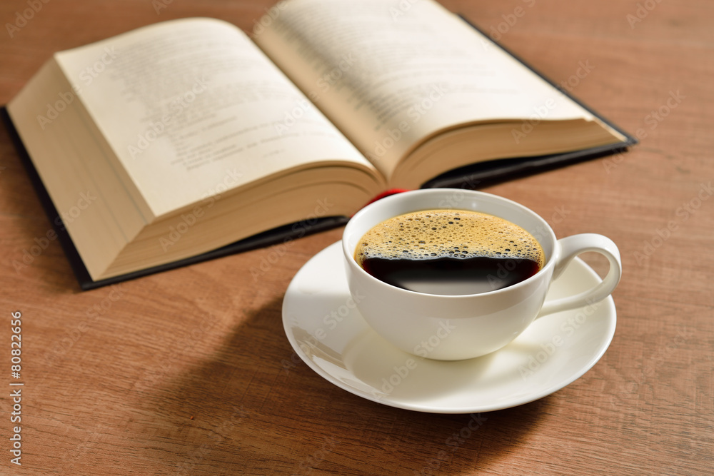 Cup of coffee and books on wooden table