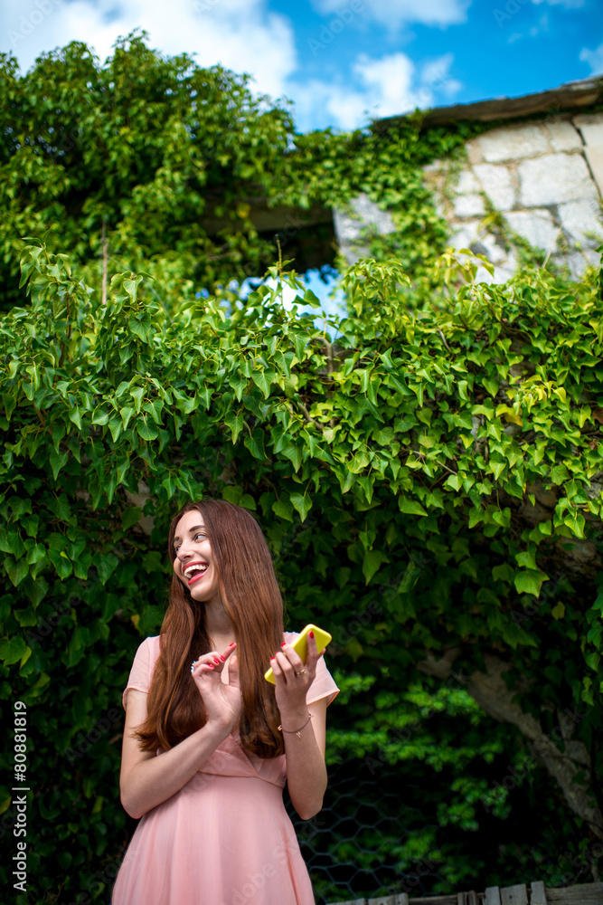 Woman using phone on green ivy background