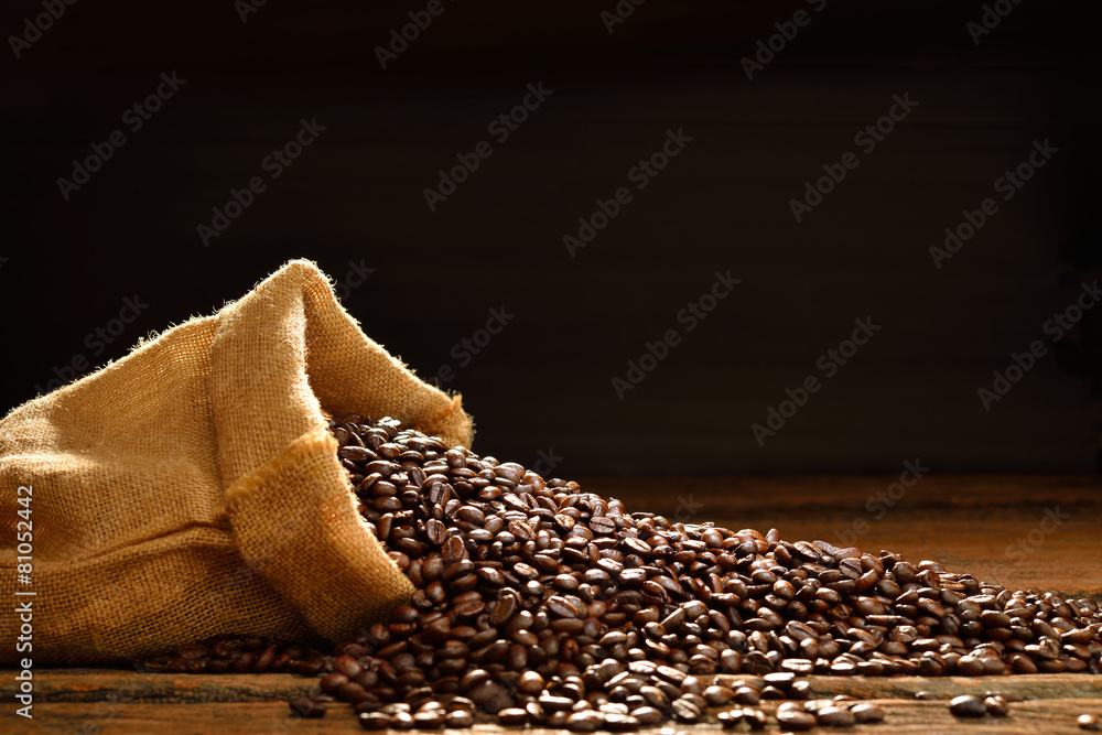 Coffee beans in burlap sack on wooden table