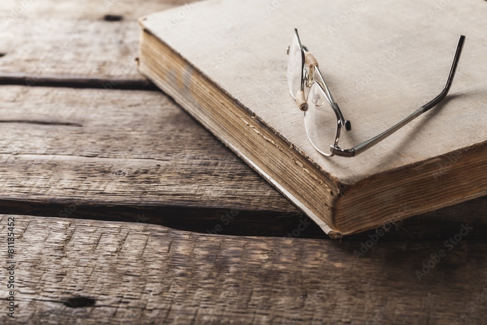 Antique. Old book and glasses on brown wooden planks background