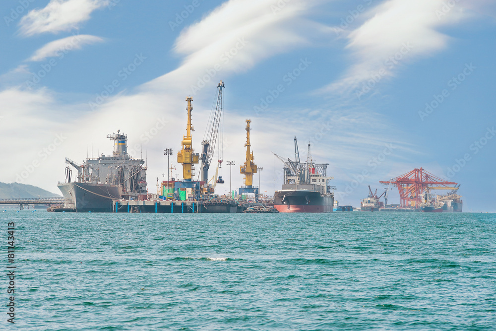 Container Cargo freight ship with working crane bridge in shipya