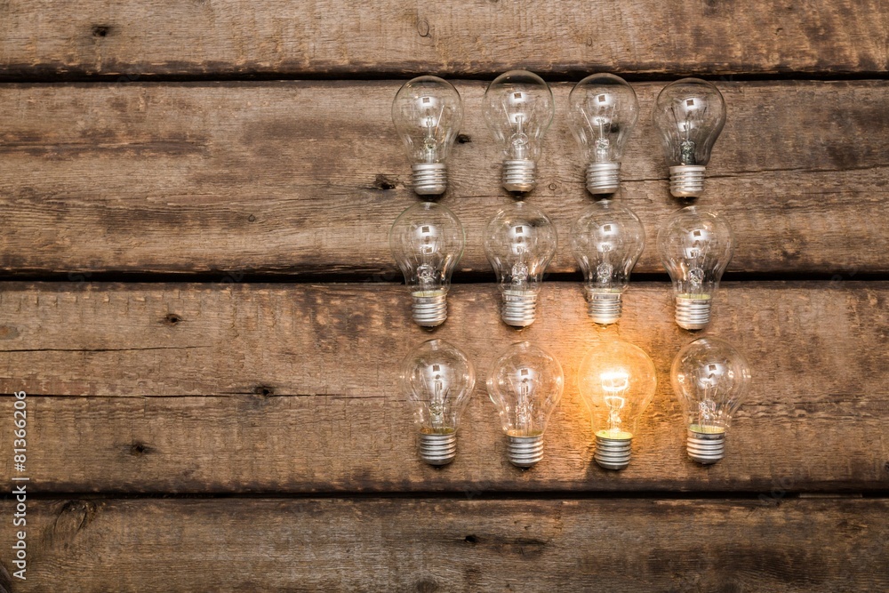 Background. Glowing bulb uniqueness concept on brown wooden