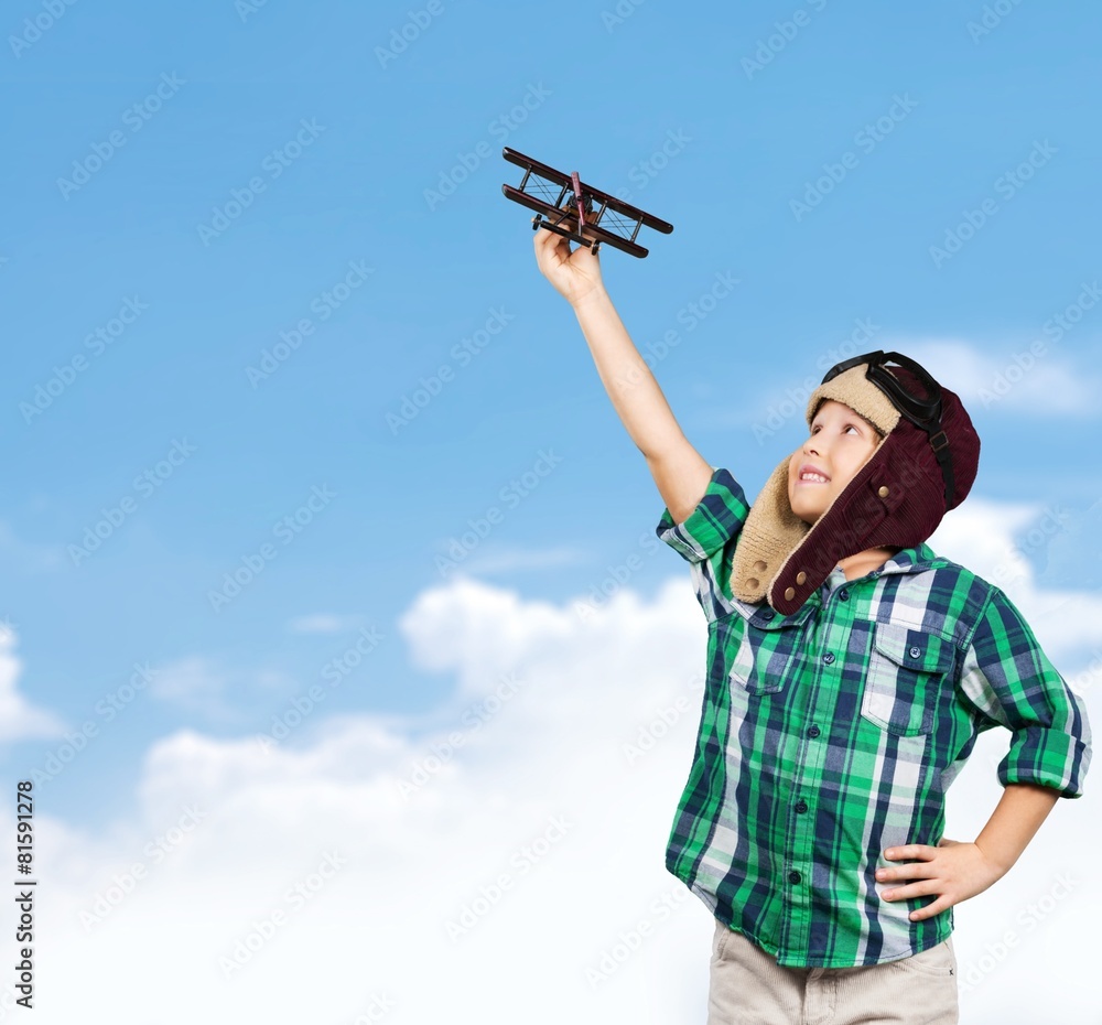 Child. Boy in helmet pilot playing with a toy wooden airplane in