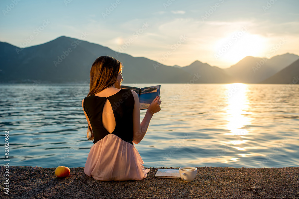 Young woman sitting on the pier at sunrise