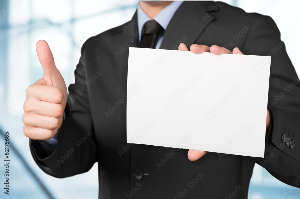 Anger. Businessman covering his face with angry mask on gray