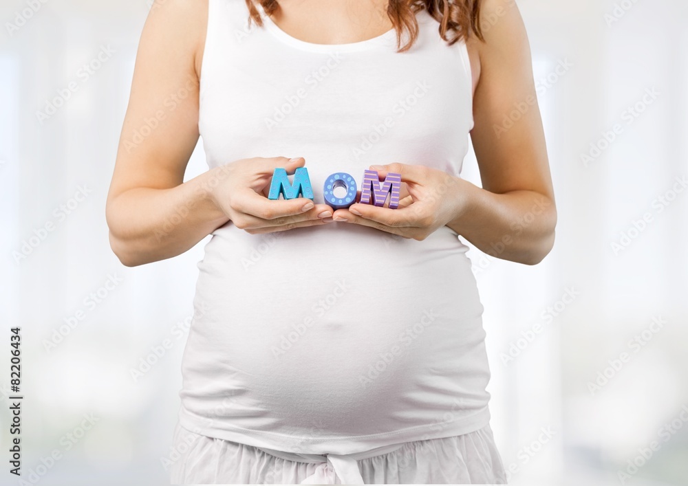 Pregnant. Pregnant woman holding a letter from plastic - m o m -