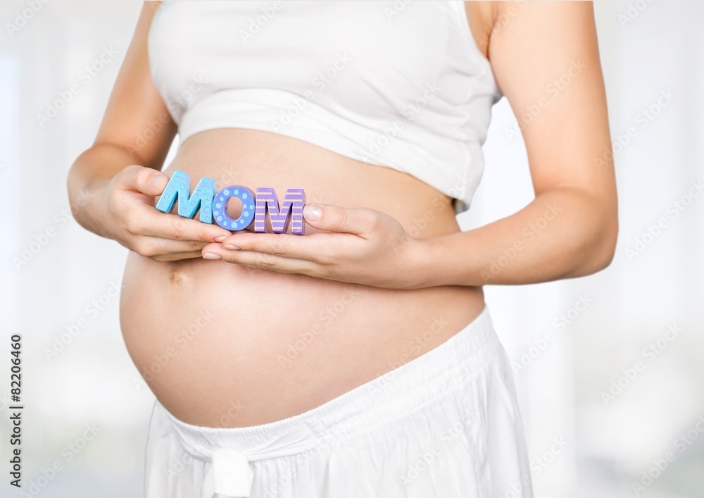 Pregnant. Pregnant woman holding a letter from plastic - m o m -