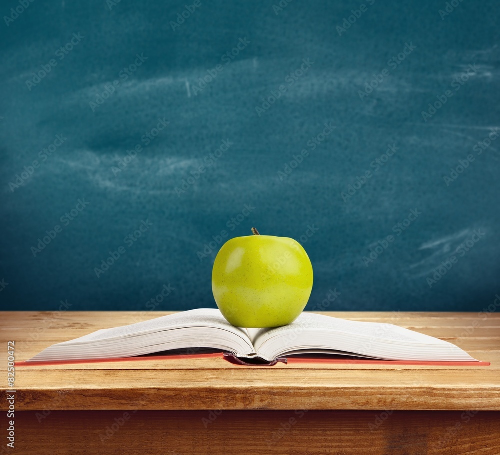 Book. Green apple on a red book, isolated