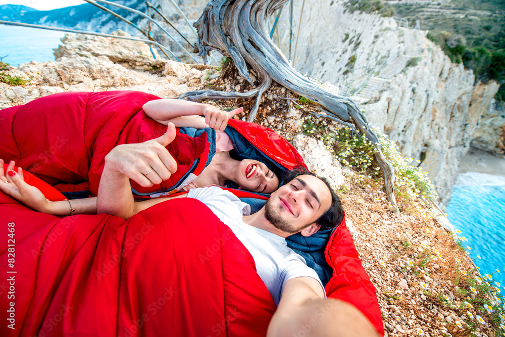 Young couple in sleeping bags near the sea