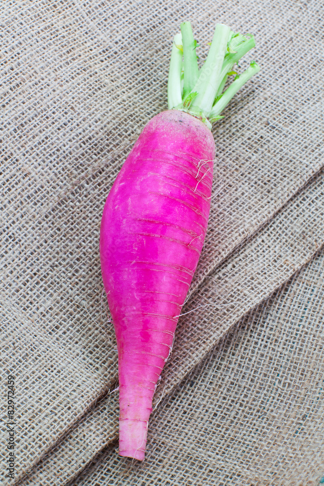  Large and fresh purple daikon radish on brown fabric background