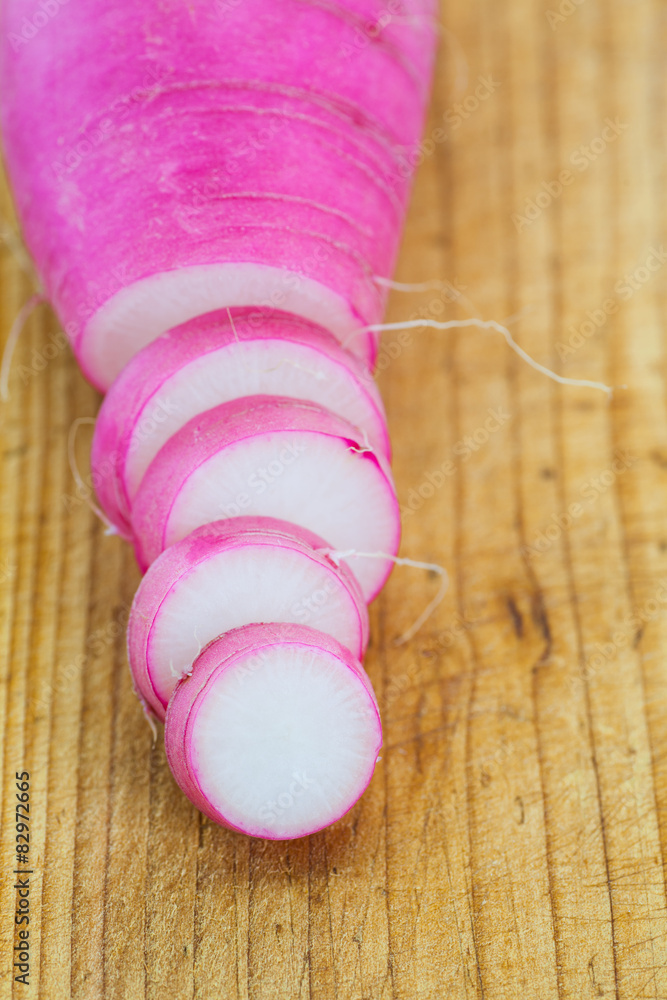 fresh purple daikon radish slice on brown wood background.