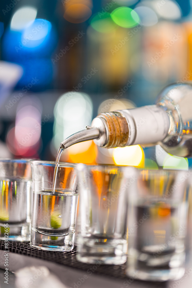 Barman pouring hard spirit into glasses